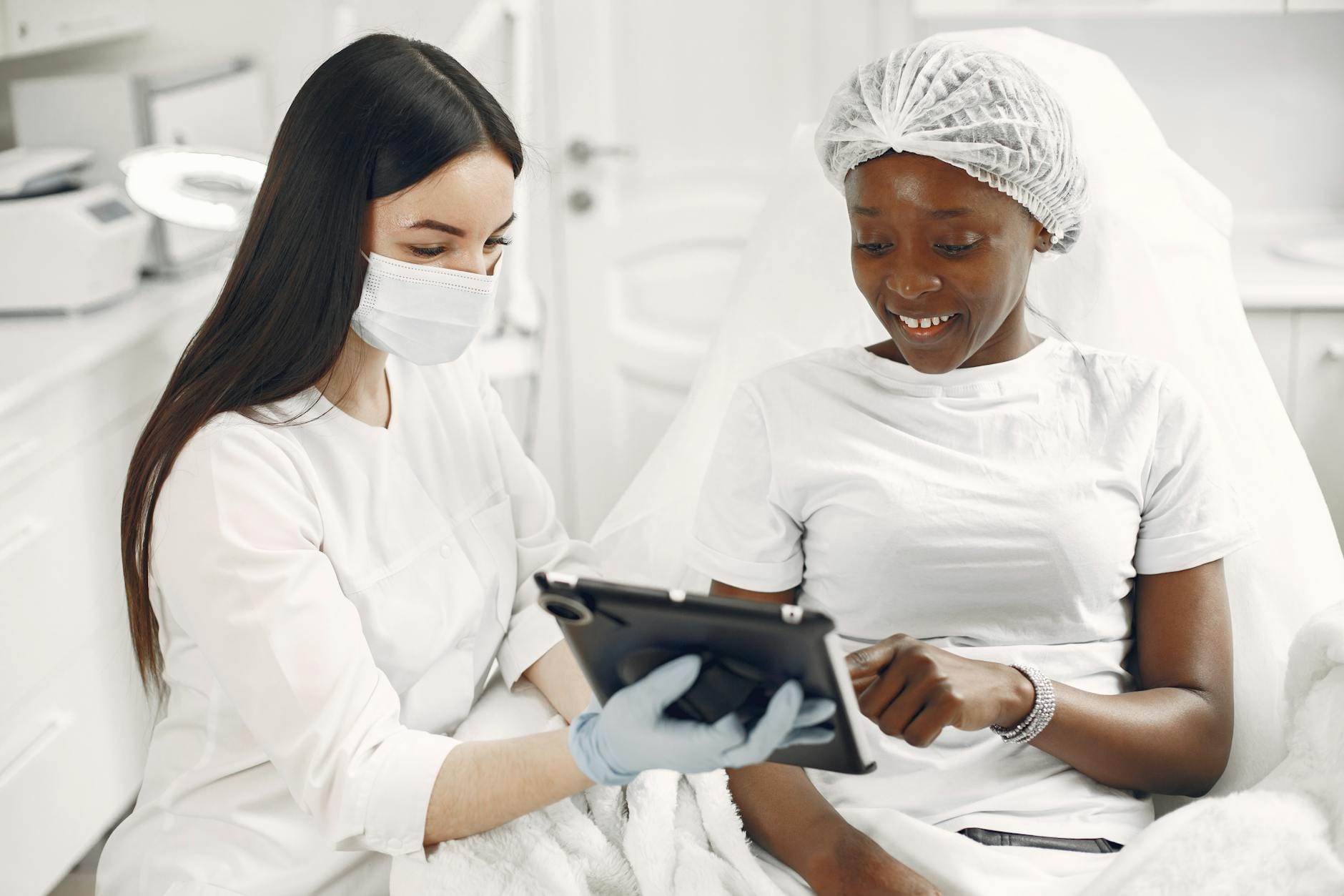 Dermatolog omawia z uśmiechniętą pacjentką wyniki skóry na tablecie