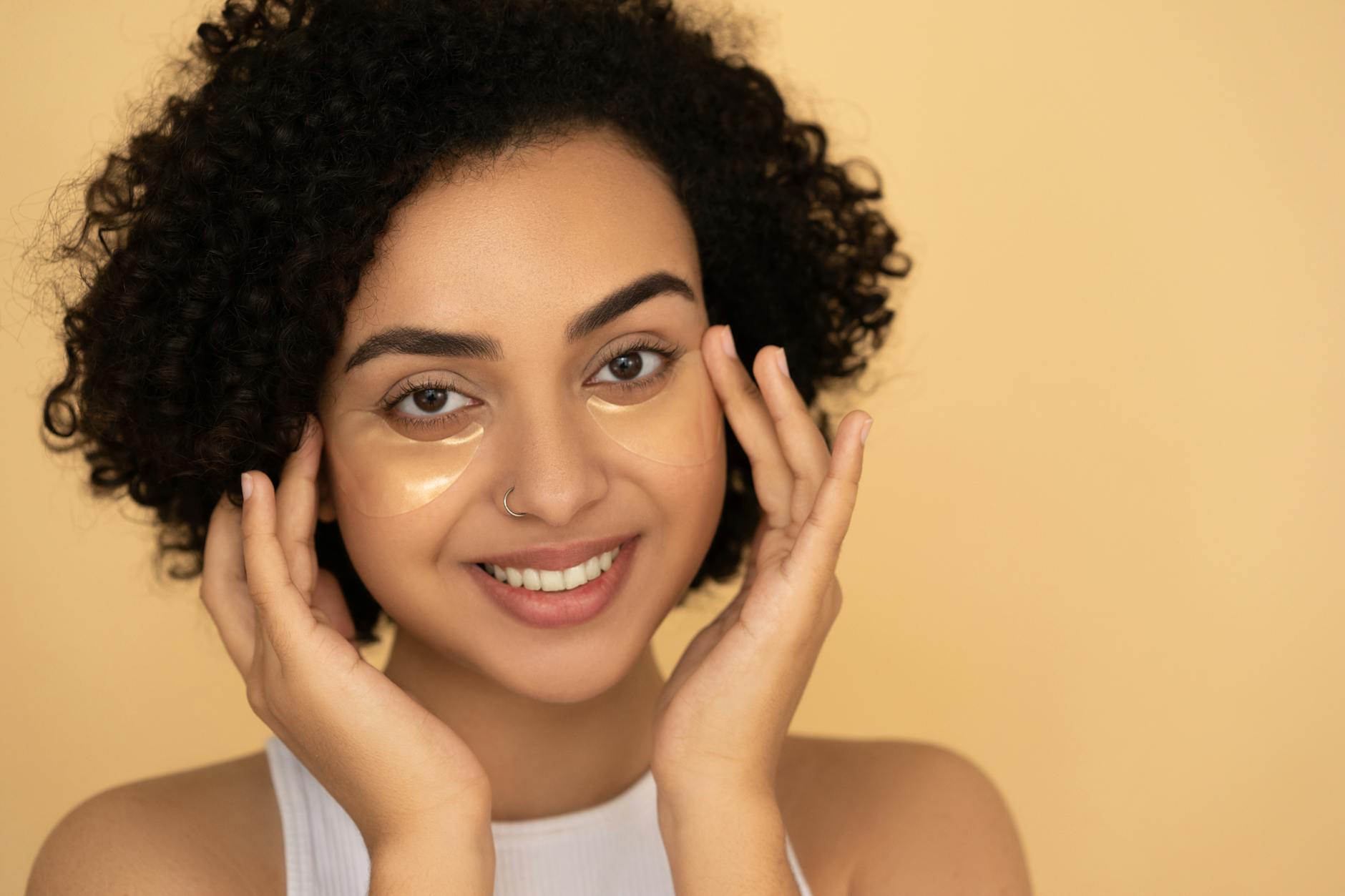 Uśmiechnięta kobieta z kręconymi włosami w płatkach pod oczy