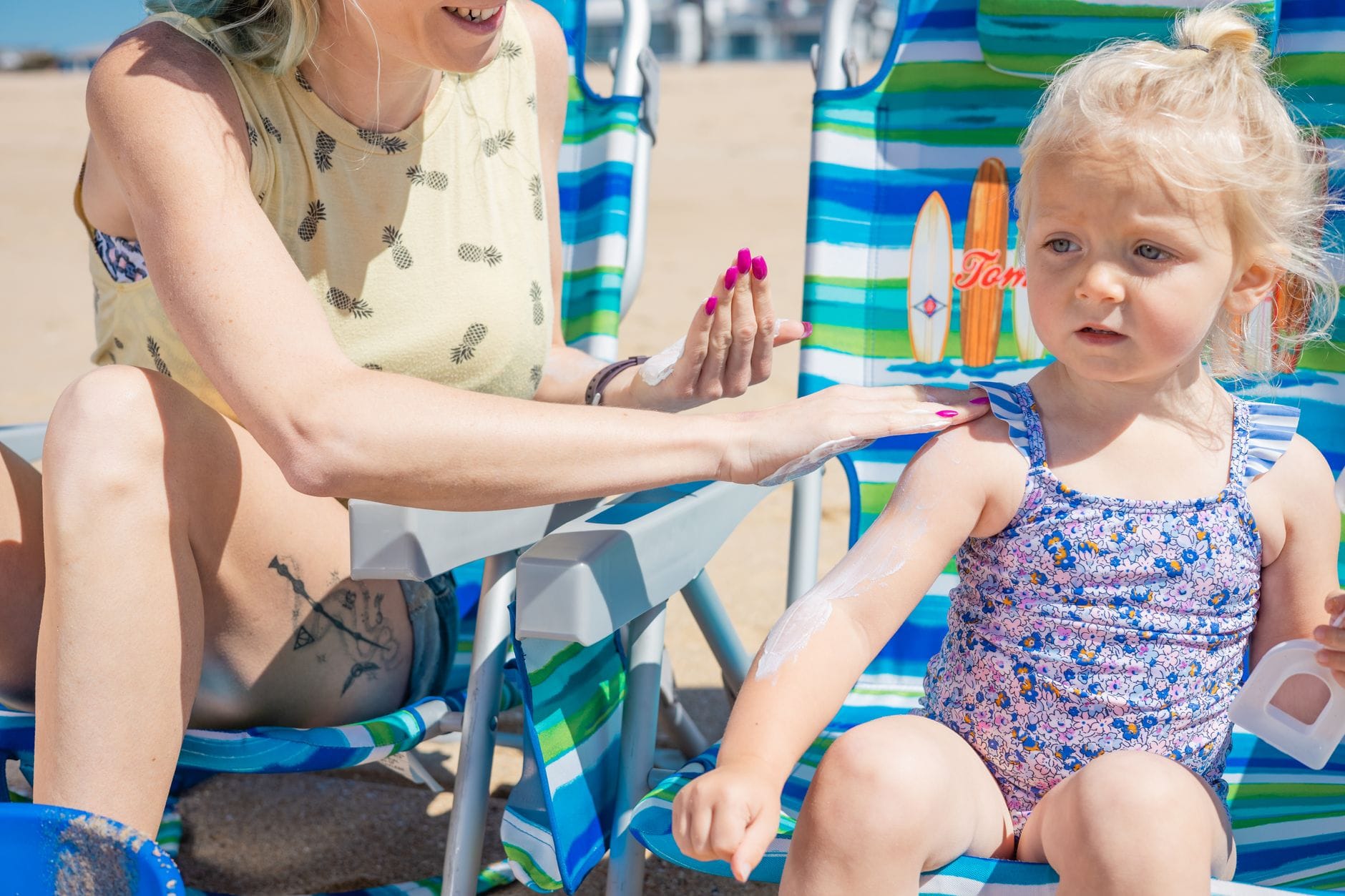 Mama nakłada córce krem z filtrem na plaży w słoneczny dzień