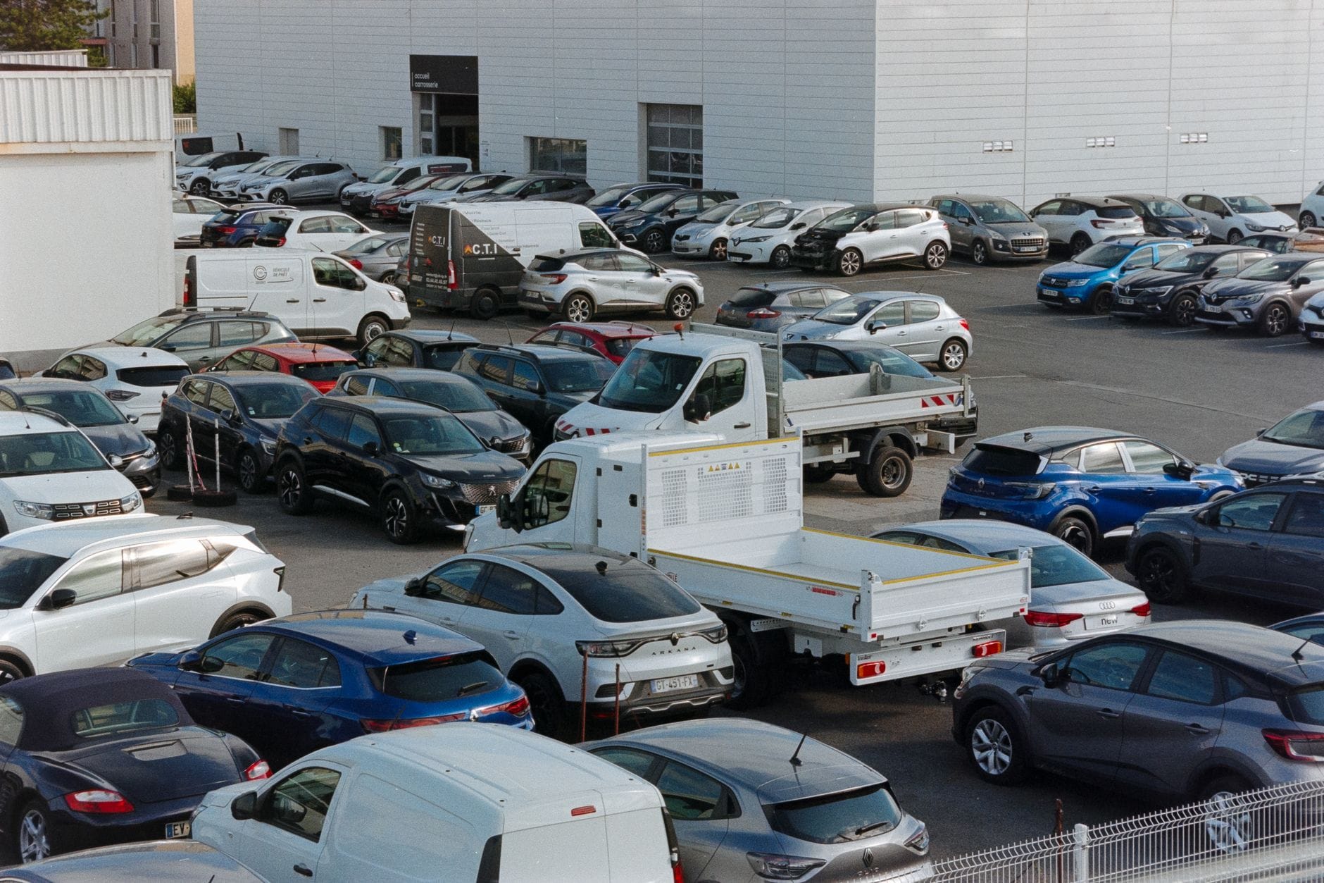 Zatłoczony parking z zaparkowanymi samochodami osobowymi i dostawczymi